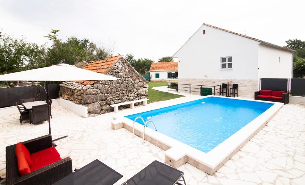 einem Pool mit Stühlen und einem Sonnenschirm neben einem Haus in der Unterkunft Holiday Home Relax in Neorić