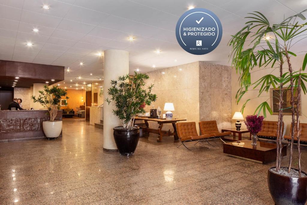un hall avec des tables et des plantes en pot dans un bâtiment dans l'établissement Hotel Rojas All Suite, à São Paulo