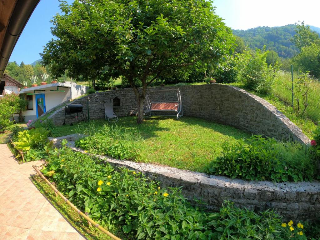 a stone retaining wall with a bench in a garden at Apartments Denis in Tolmin