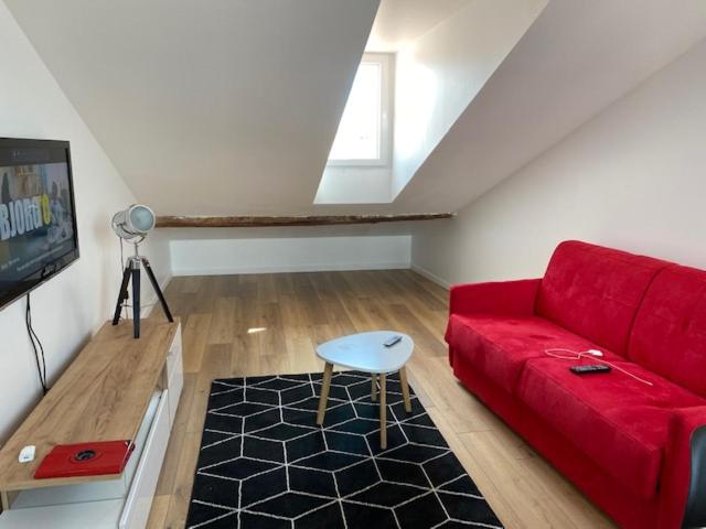 un salon avec un canapé rouge et une télévision dans l'établissement appartement à 100 m de la plage, à Cannes