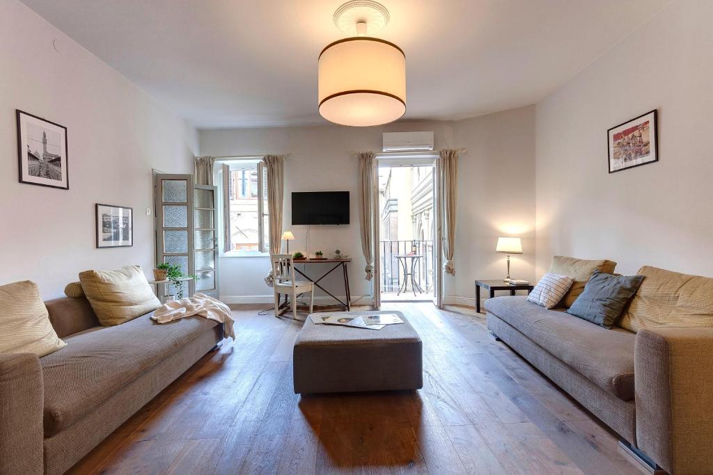 ein Wohnzimmer mit 2 Sofas und einem TV in der Unterkunft Mamo Florence - Nori Apartment in Florenz