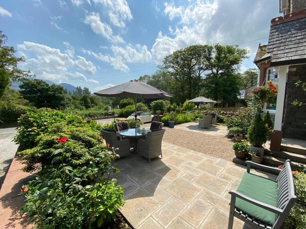 um pátio com uma mesa, cadeiras e um guarda-sol em Lakeside Country Guest House em Bassenthwaite Lake