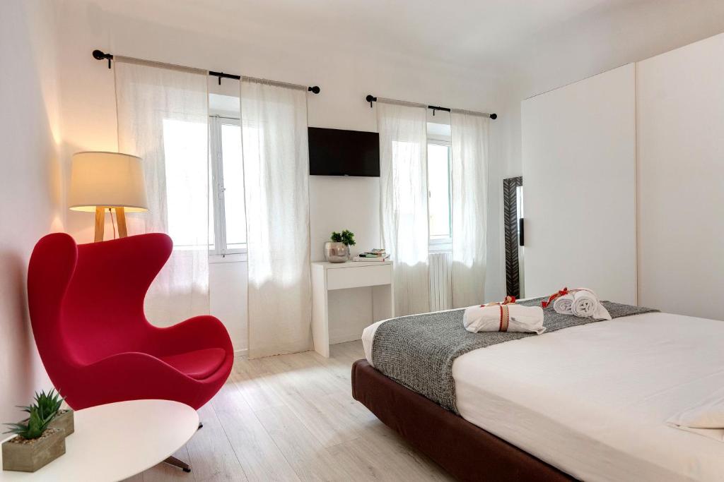 Schlafzimmer mit einem roten Stuhl und einem Bett in der Unterkunft Mamo Florence - Velluti Apartment in Florenz