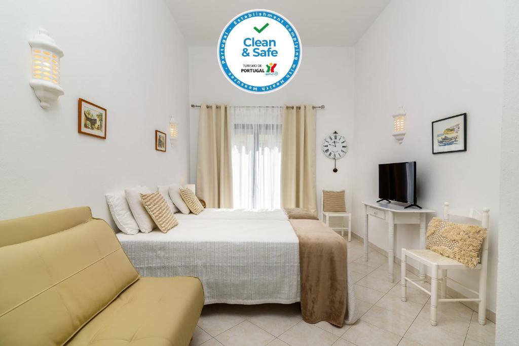 a bedroom with a bed and a couch and a tv at Sunrise Apartment I in Carvoeiro