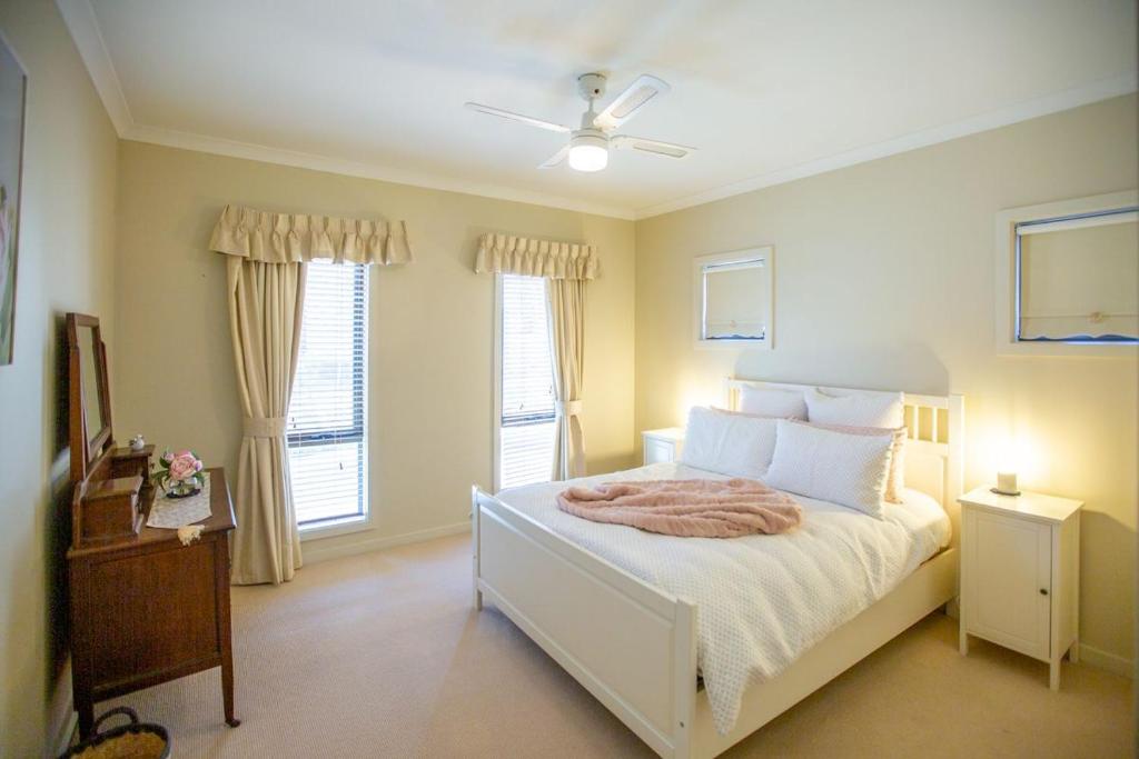 a bedroom with a white bed and two windows at Paula's Place 8 Ti Tree Close Robe in Robe