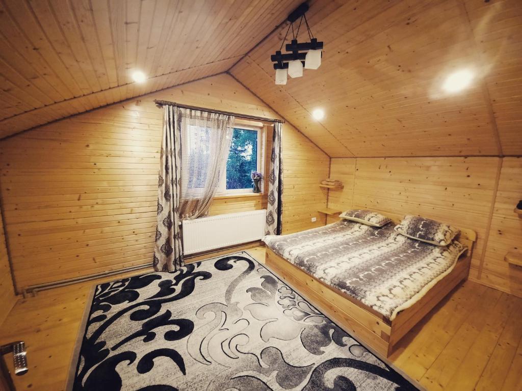 sypialnia w drewnianym domku z łóżkiem i dywanem w obiekcie У Мар'яни w mieście Worochta
