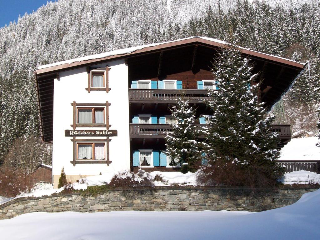 ein Gebäude im Schnee mit einem Baum davor in der Unterkunft Gästehaus Sahler in Gaschurn