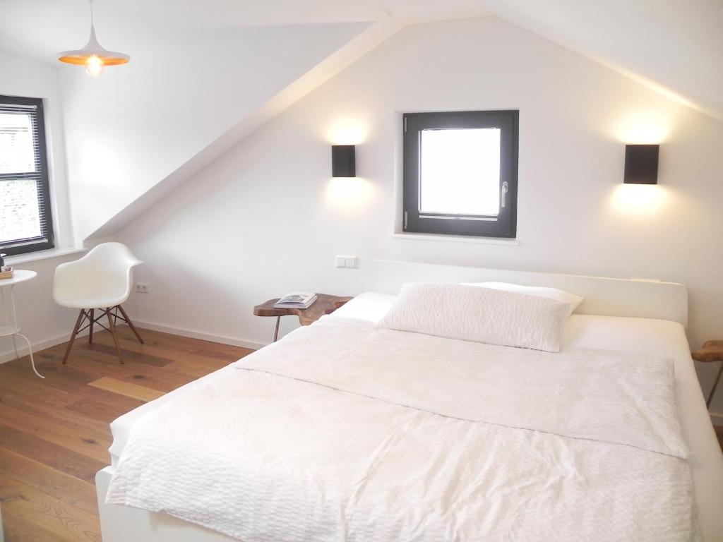 a white bedroom with a white bed and a window at Milchhaus Zimmer - Tiny House in Balingen