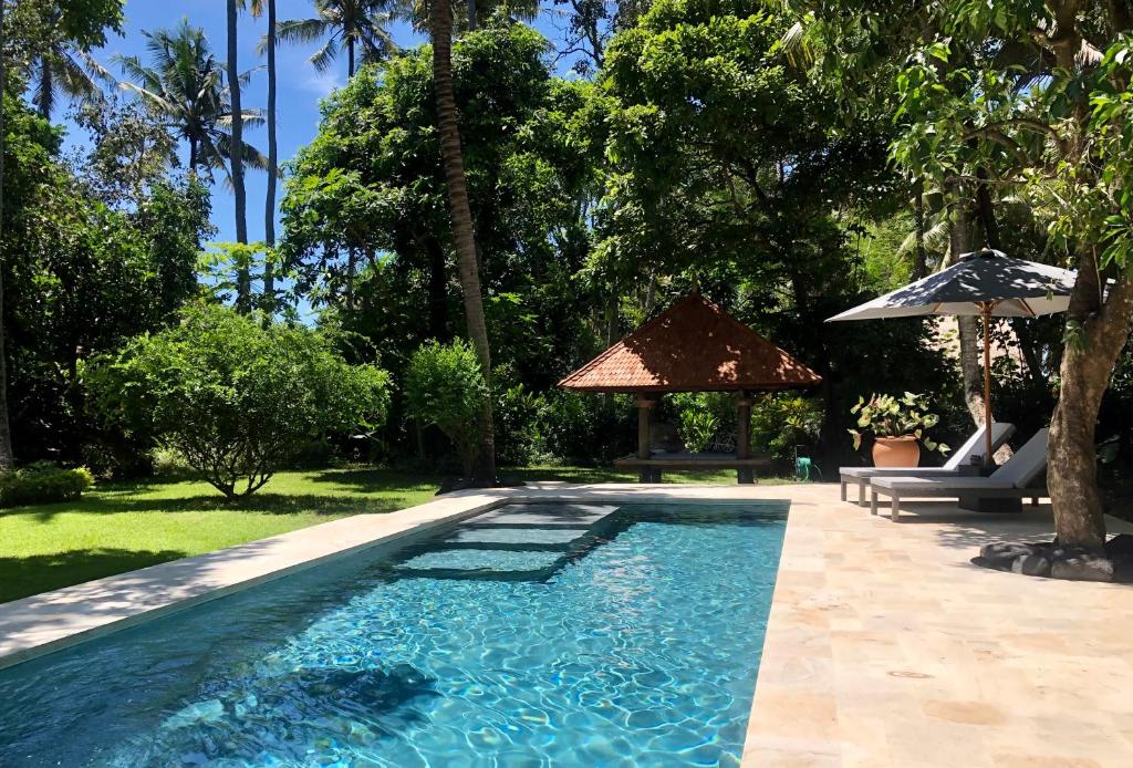 JasriにあるHIDDEN HEAVEN Rumah Barongの傘付きの庭のスイミングプール