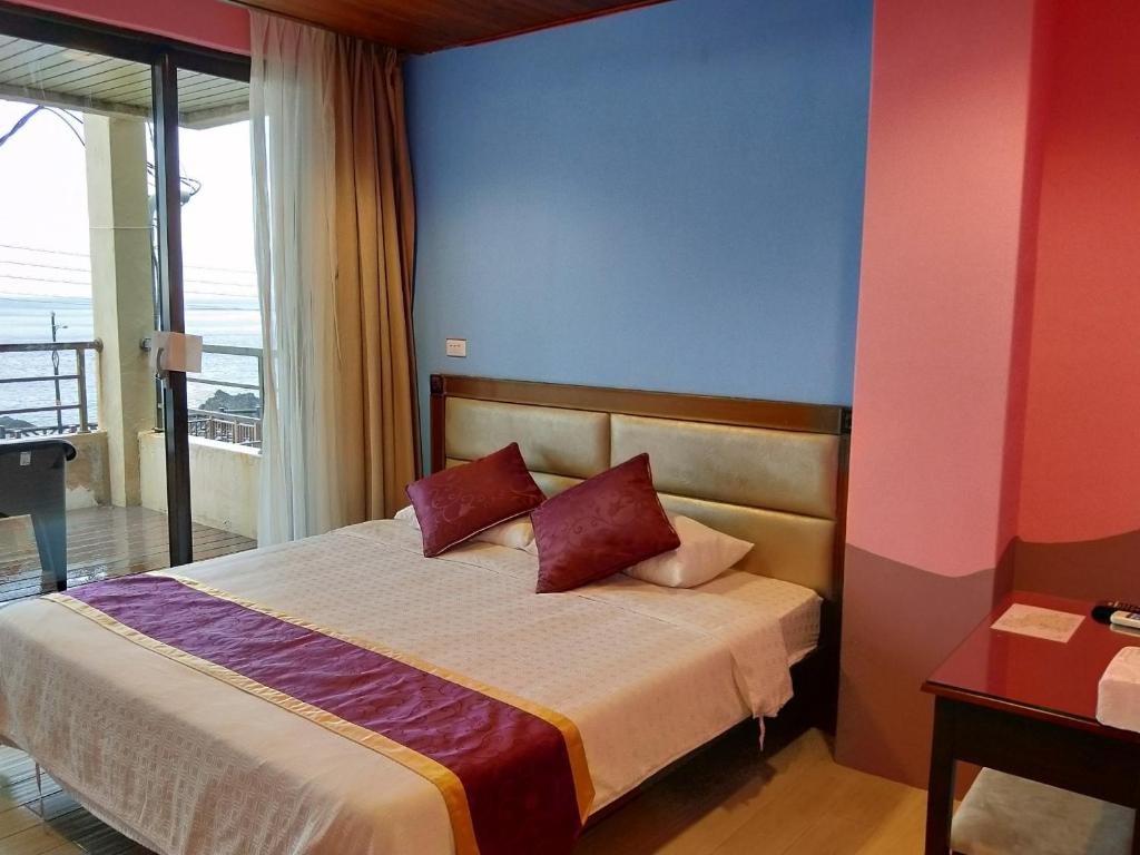 1 dormitorio con 1 cama con paredes rojas y azules en Two Fish Homestay en Lanyu