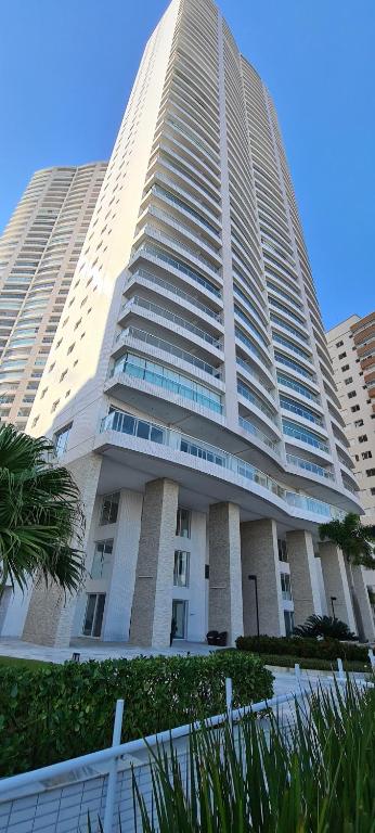 un grande edificio bianco con una palma di fronte di Mar doce lar a Praia Grande