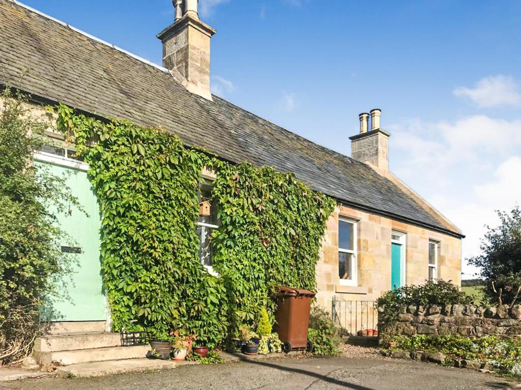 an ivy covered house with a green door at Borthwick Castle View in North Middleton