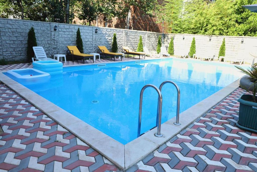 a swimming pool with blue water in a backyard at Hotel Estonia Two in Kobuleti