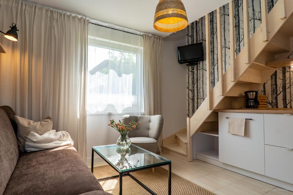 a living room with a couch and a glass table at Domki Letniskowe AlexJan in Dąbki