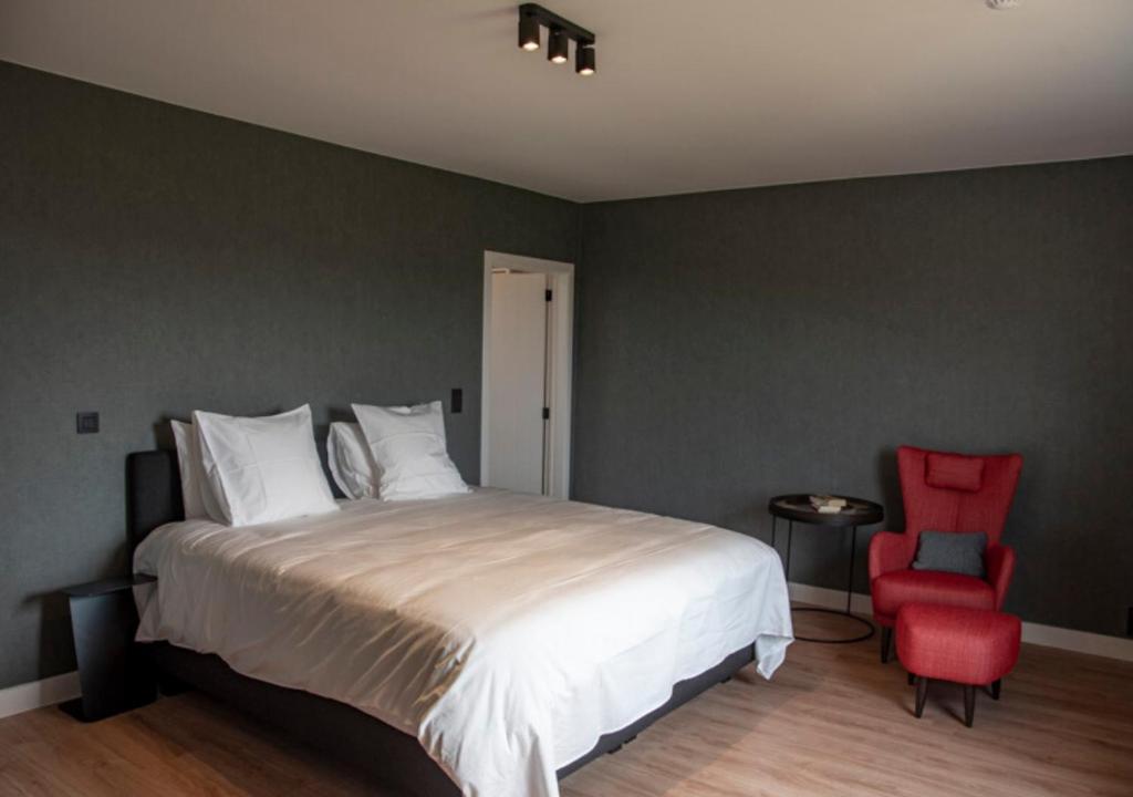 a bedroom with a large bed and a red chair at XXV House - 12 personnes in Héron