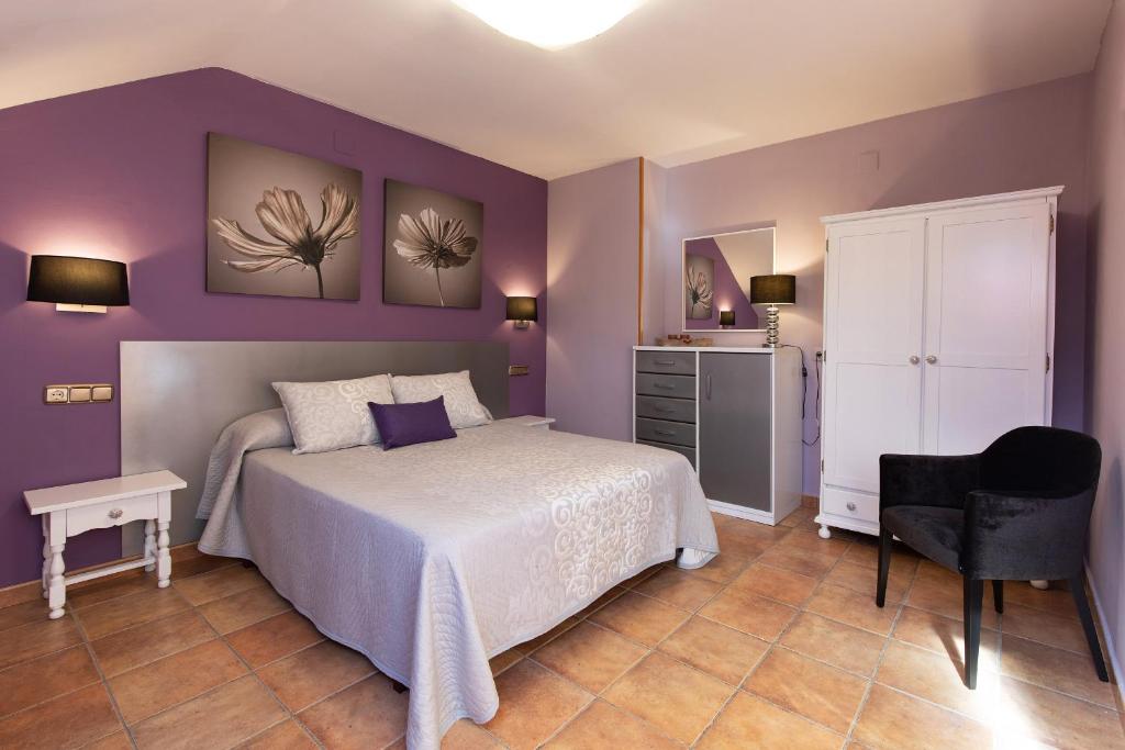 Dormitorio púrpura con cama y silla en Apartamentos Cinca, en Escalona