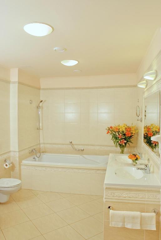 a bathroom with a tub and a toilet and a sink at Interhotel Central in Karlovy Vary