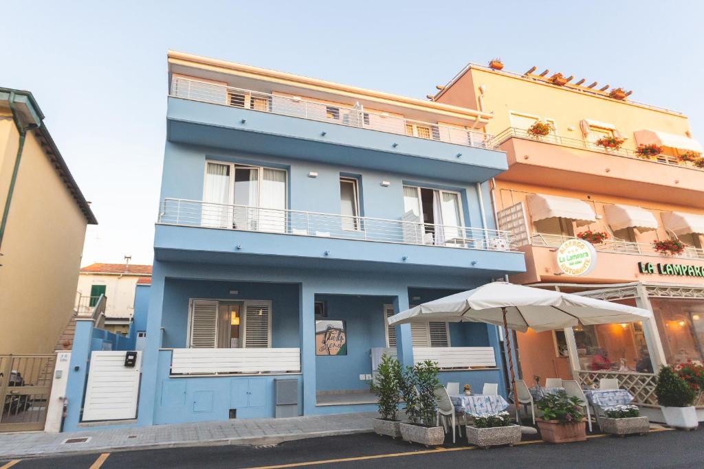 un edificio azul con un paraguas delante en Via Siena 4 - Suites & Rooms en Marina di Cecina