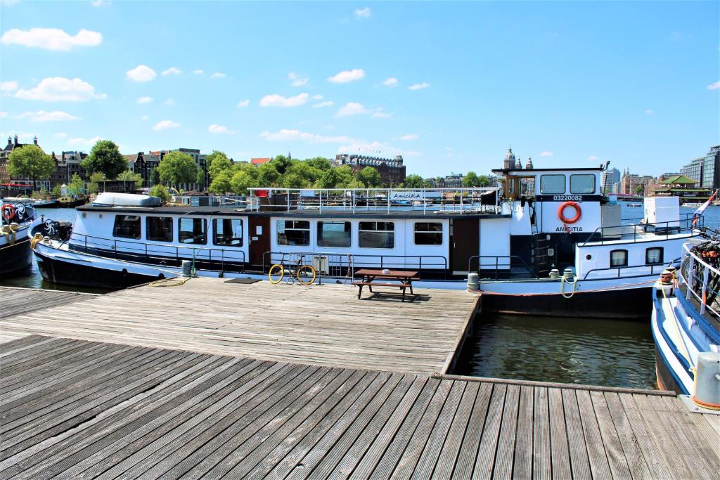 two boats docked at a dock with a picnic table at AmicitiA in Amsterdam