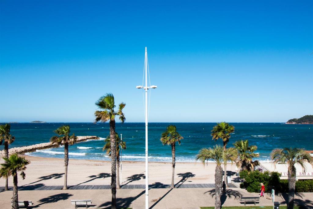 une croix sur une plage avec des palmiers et l'océan dans l'établissement Hôtel Bel Azur, à Six-Fours-les-Plages
