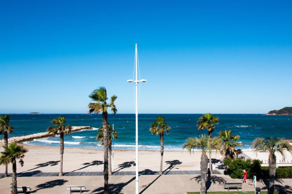 una cruz en una playa con palmeras y el océano en Hôtel Bel Azur, en Six-Fours-les-Plages