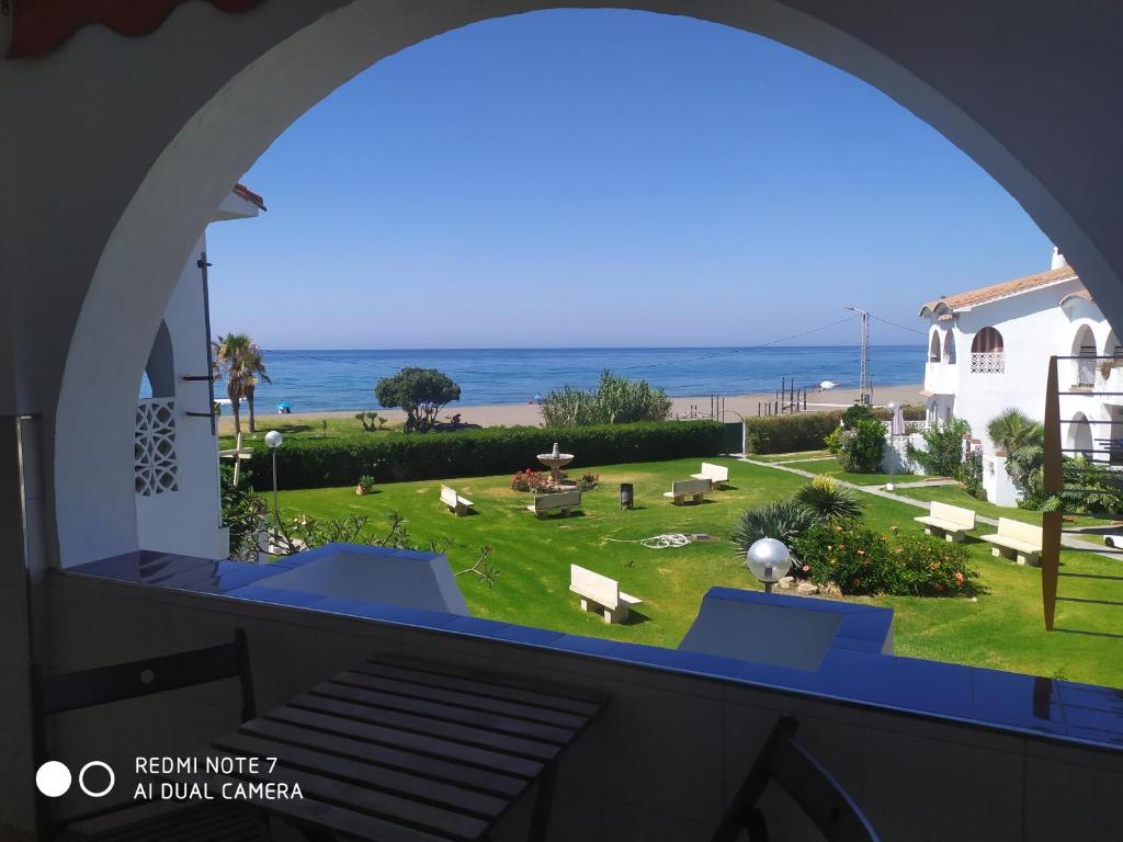 a view of a park from a window with the ocean at BUNGALOW CHARO in Torre de Benagalbón