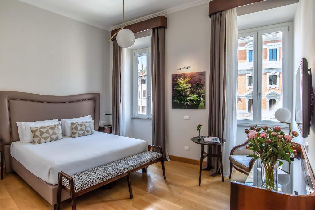 a bedroom with a bed and a chair and windows at Relais Rione Ponte in Rome