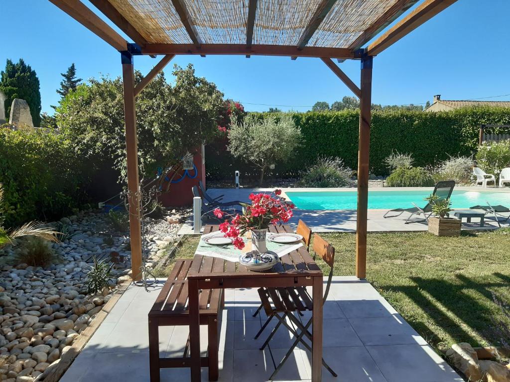 a table and chairs under a pergola next to a pool at Le mazet de l'Amathye in Aramon