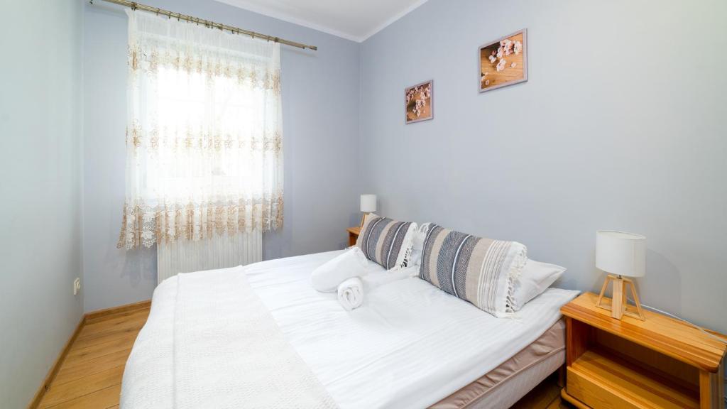 a bedroom with a bed with white sheets and a window at Apartamenty EverySky - Olimpijska 3 in Karpacz