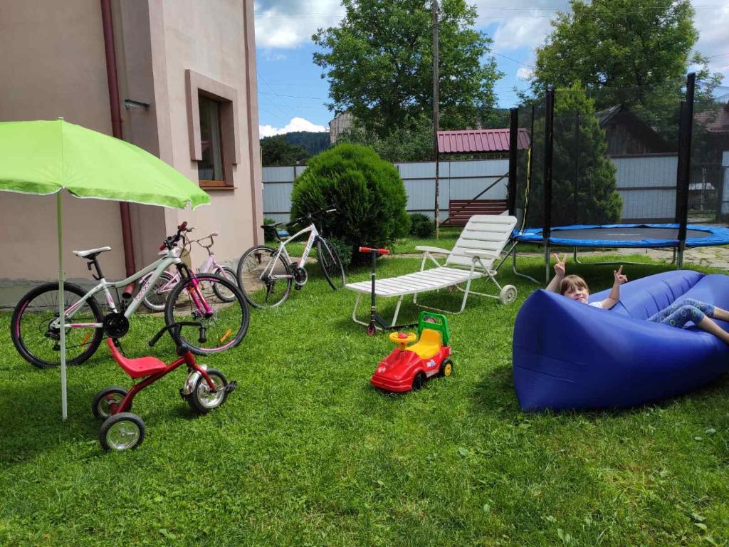 a child laying on the grass in a backyard with toys at Нота Карпат in Skole