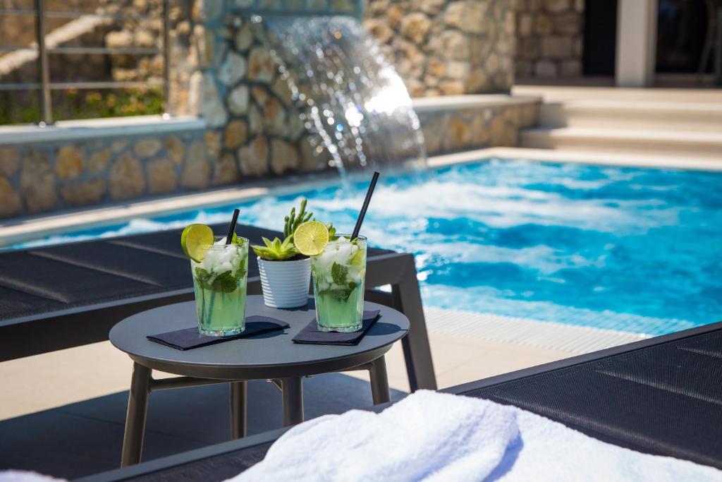dos cócteles en una mesa junto a la piscina en Villa Madrevita Exclusive, en Zaton