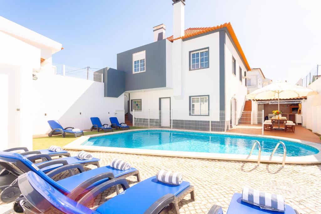 a villa with a swimming pool and lounge chairs at Villa Sol e Mar in Charneca