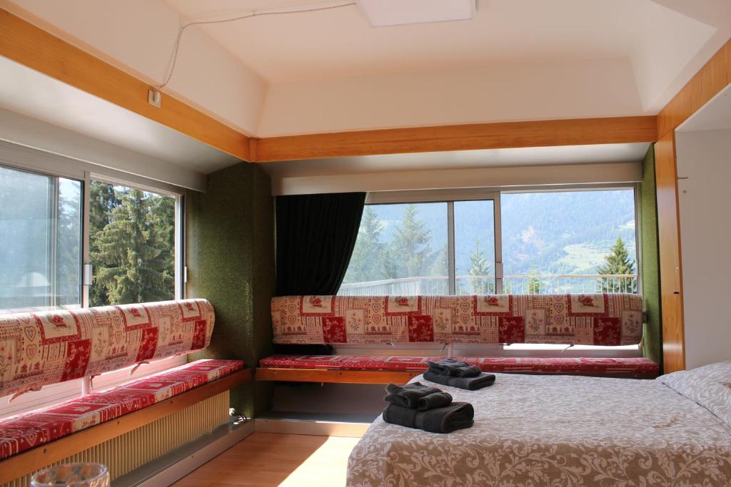 Cette chambre comprend deux lits et de grandes fenêtres. dans l'établissement IL Gatto delle Nevi, à Marilleva