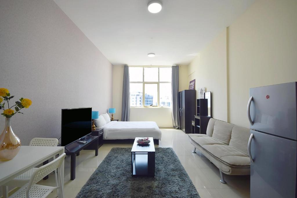 a room with a bed and a living room with a refrigerator at KeyHost - Frankfurt 1307 in Dubai