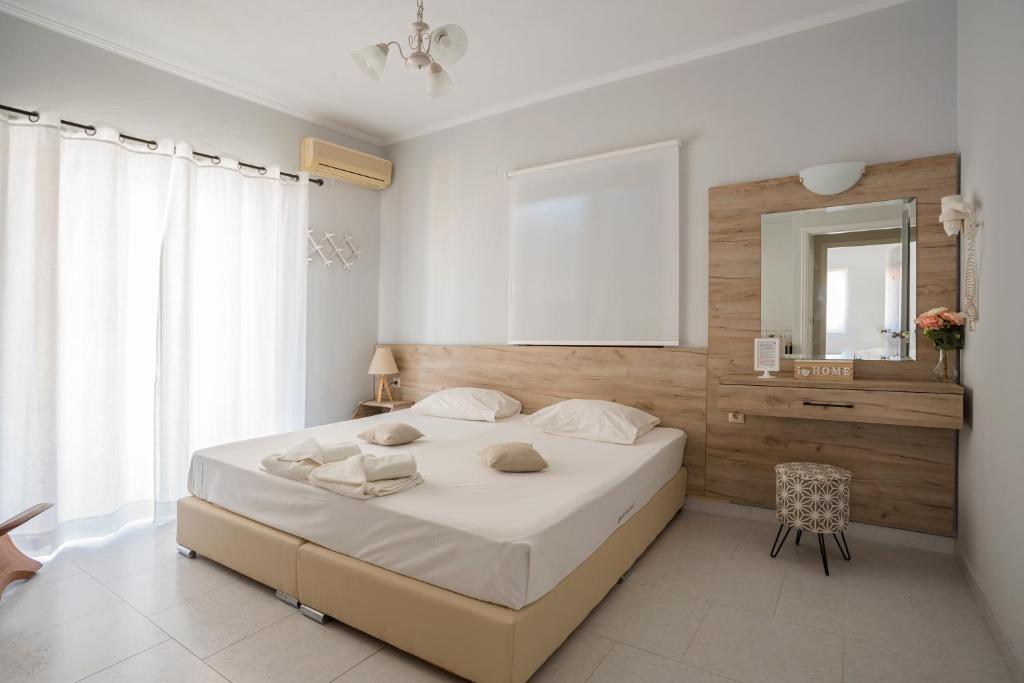 1 dormitorio con 1 cama blanca grande y espejo en Aggelos Apartments & Deluxe Studios en Nydri