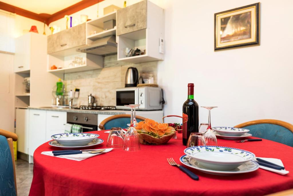 a dining table with a red table cloth and a bottle of wine at Apartman Maya in Mali Lošinj