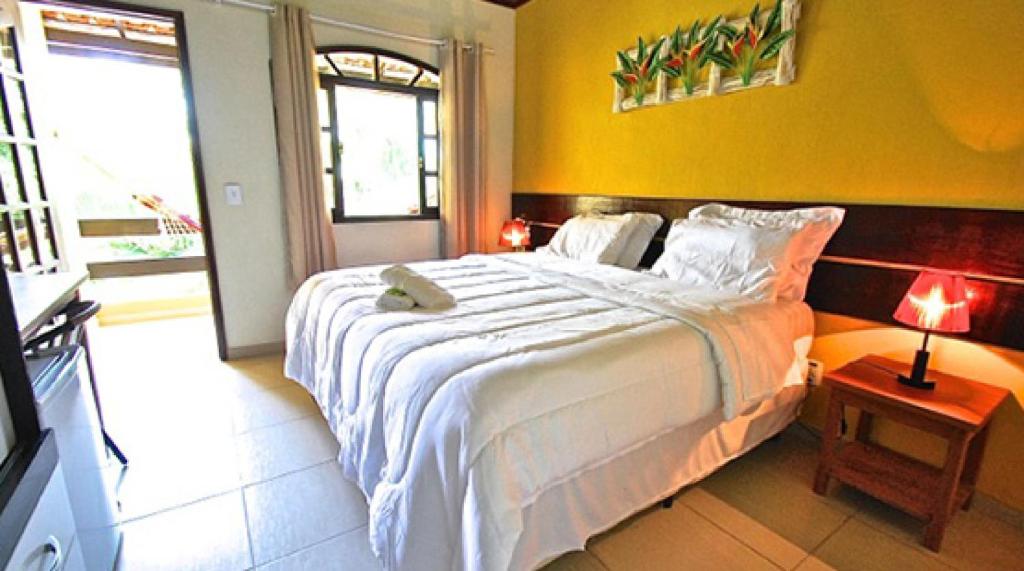 a bedroom with a large bed and a large window at Pousada Rio Bracuhy in Angra dos Reis