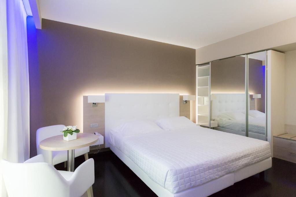 a bedroom with a white bed and a table and a mirror at Raffaello Hotel & Mooka Restaurant in Senigallia