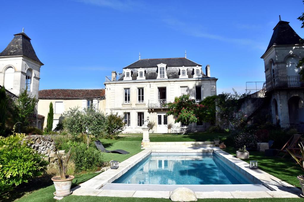 ein großes weißes Haus mit einem Pool im Hof in der Unterkunft Les Hirondelles in Fléac