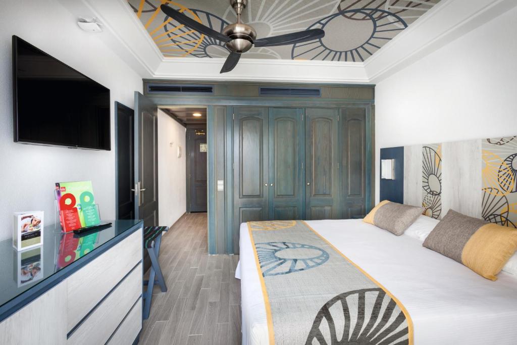 a bedroom with a bed and a ceiling fan at Hotel Riu Vistamar Gran Canaria - All Inclusive in Puerto Rico de Gran Canaria
