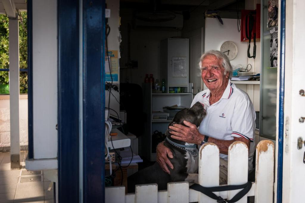 an older man holding a dog in a room at Hotel Perla in Castiglione della Pescaia