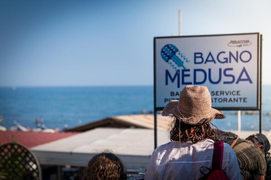 a person in a hat standing in front of a sign at Hotel Perla in Castiglione della Pescaia
