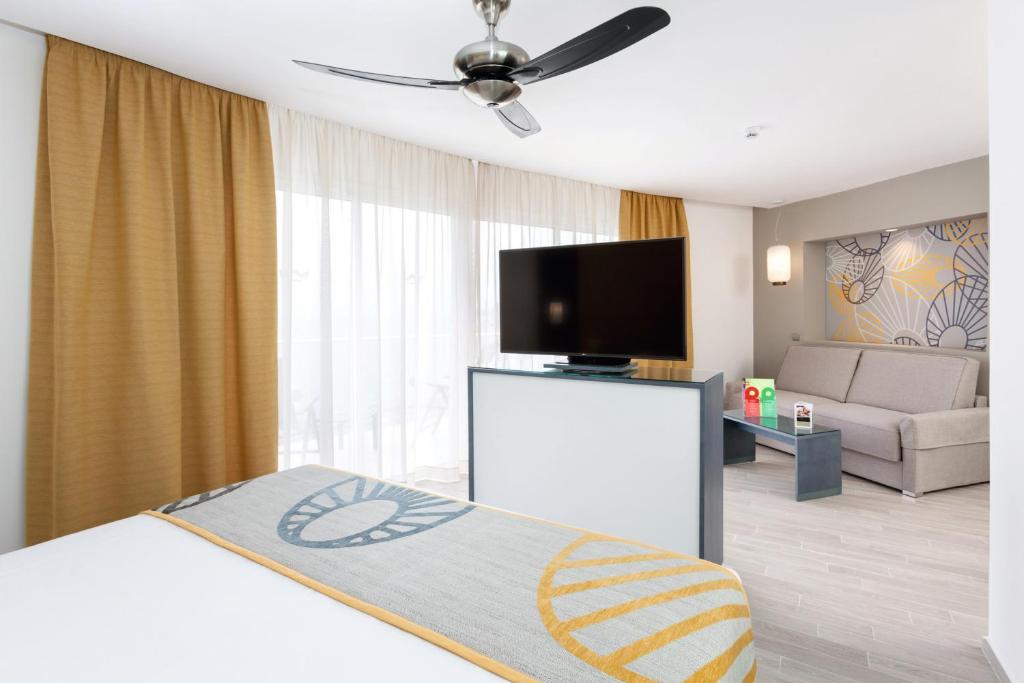 a living room with a bed and a flat screen tv at Hotel Riu Vistamar Gran Canaria - All Inclusive in Puerto Rico de Gran Canaria
