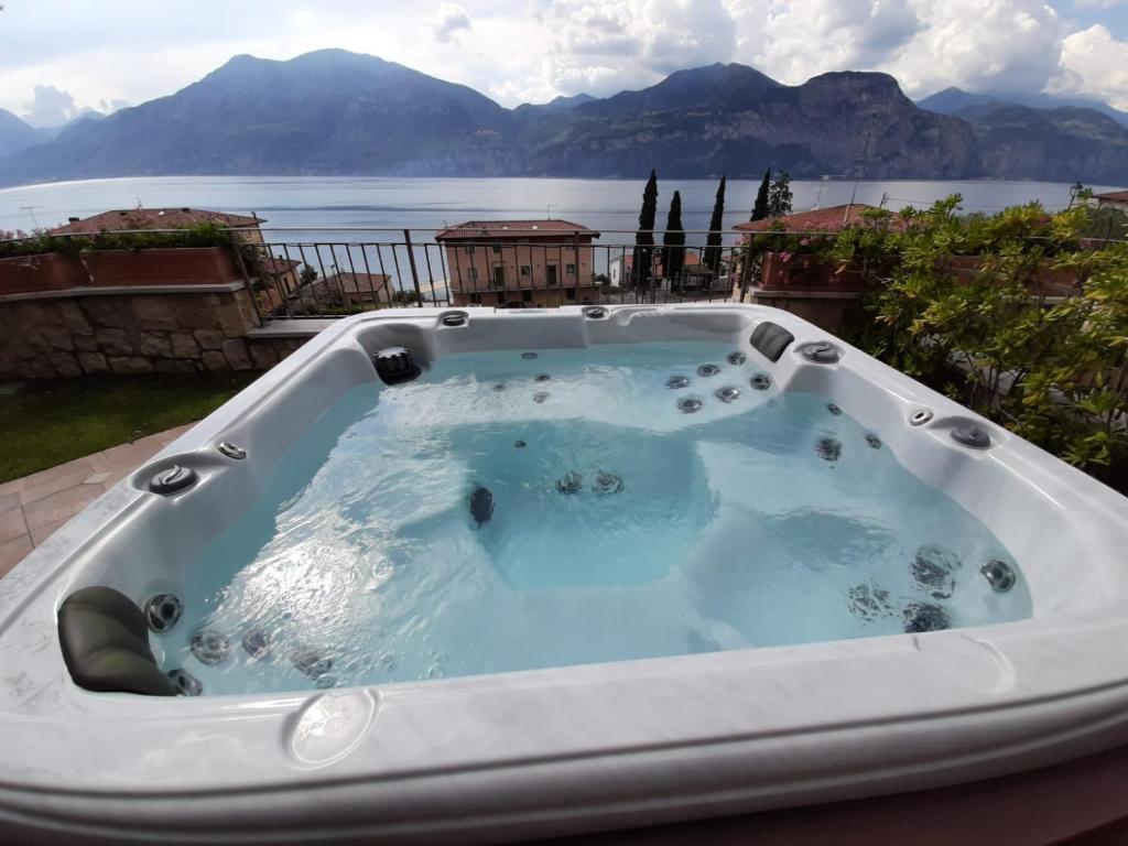 einen Whirlpool auf einer Terrasse mit Blick auf das Wasser in der Unterkunft Appartamento DELUXE 2 con vasca idromassaggio vista Lago di Garda, riscaldata, privata e utilizzabile tutto l'anno in Brenzone sul Garda