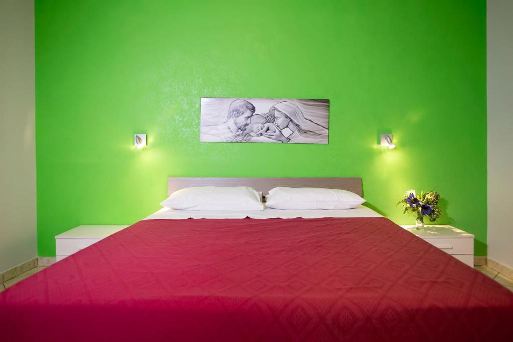1 dormitorio verde con 1 cama grande con colcha roja en Il Tipico en Trapani