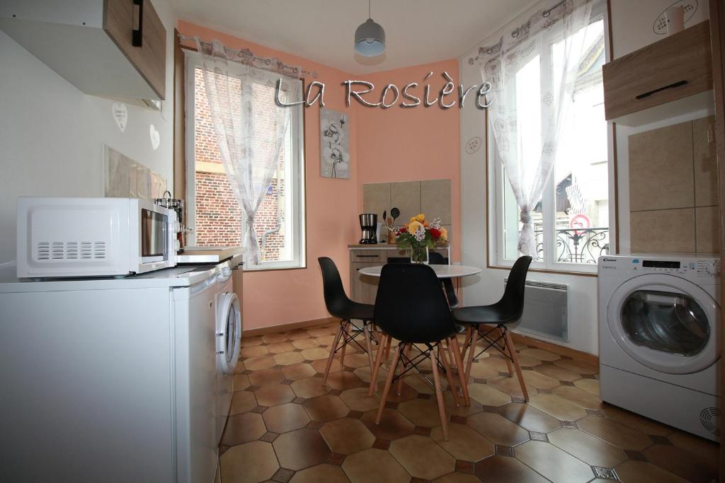 een keuken met een tafel en stoelen en een wasmachine bij LA ROSIERE in La Fère