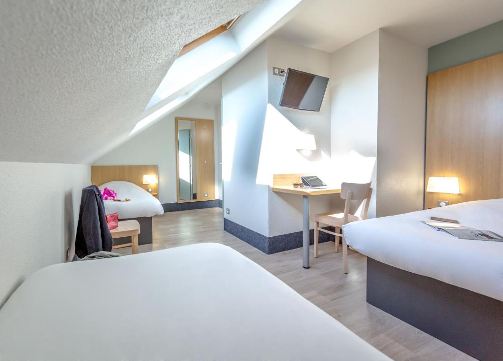 een hotelkamer met 2 bedden en een bureau bij B&B HOTEL PERPIGNAN Nord Aéroport in Perpignan