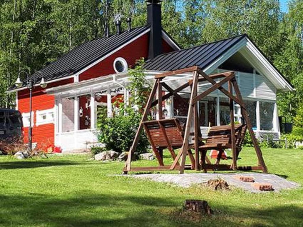 ein rotes und weißes Haus mit einer Bank davor in der Unterkunft Holiday Home Siimaranta by Interhome in Vehmersalmi