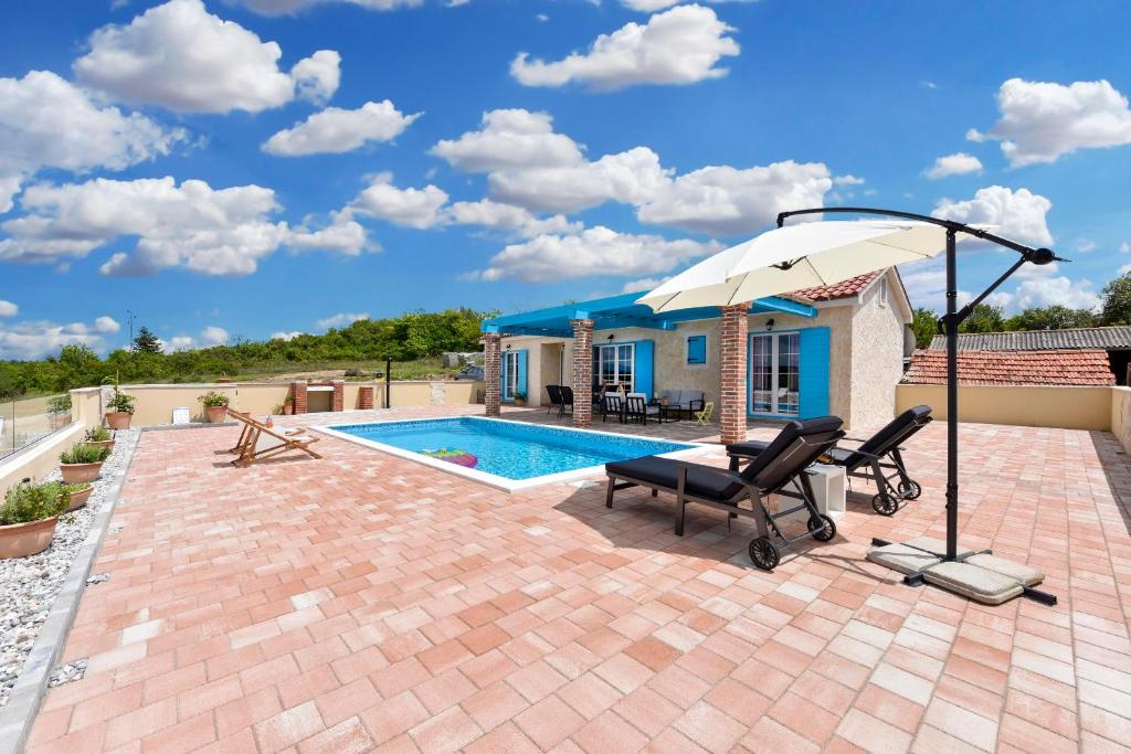 蘇科尚的住宿－Villa Jurenda，一个带两把椅子和一把遮阳伞的庭院,毗邻一个游泳池