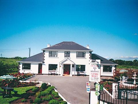 une grande maison blanche avec un panneau devant elle dans l'établissement Castle View House, à Ballylongford